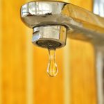 Water tap on yellow background